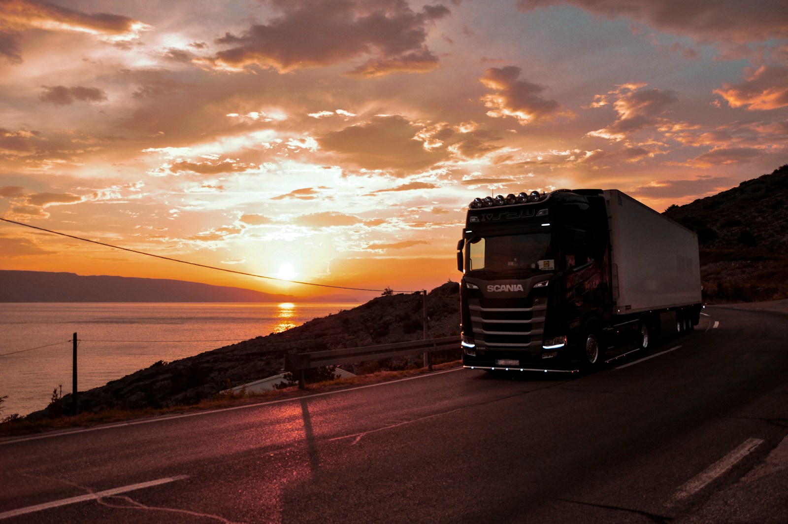 Camión transitando por carretera al atardecer cerca del mar
